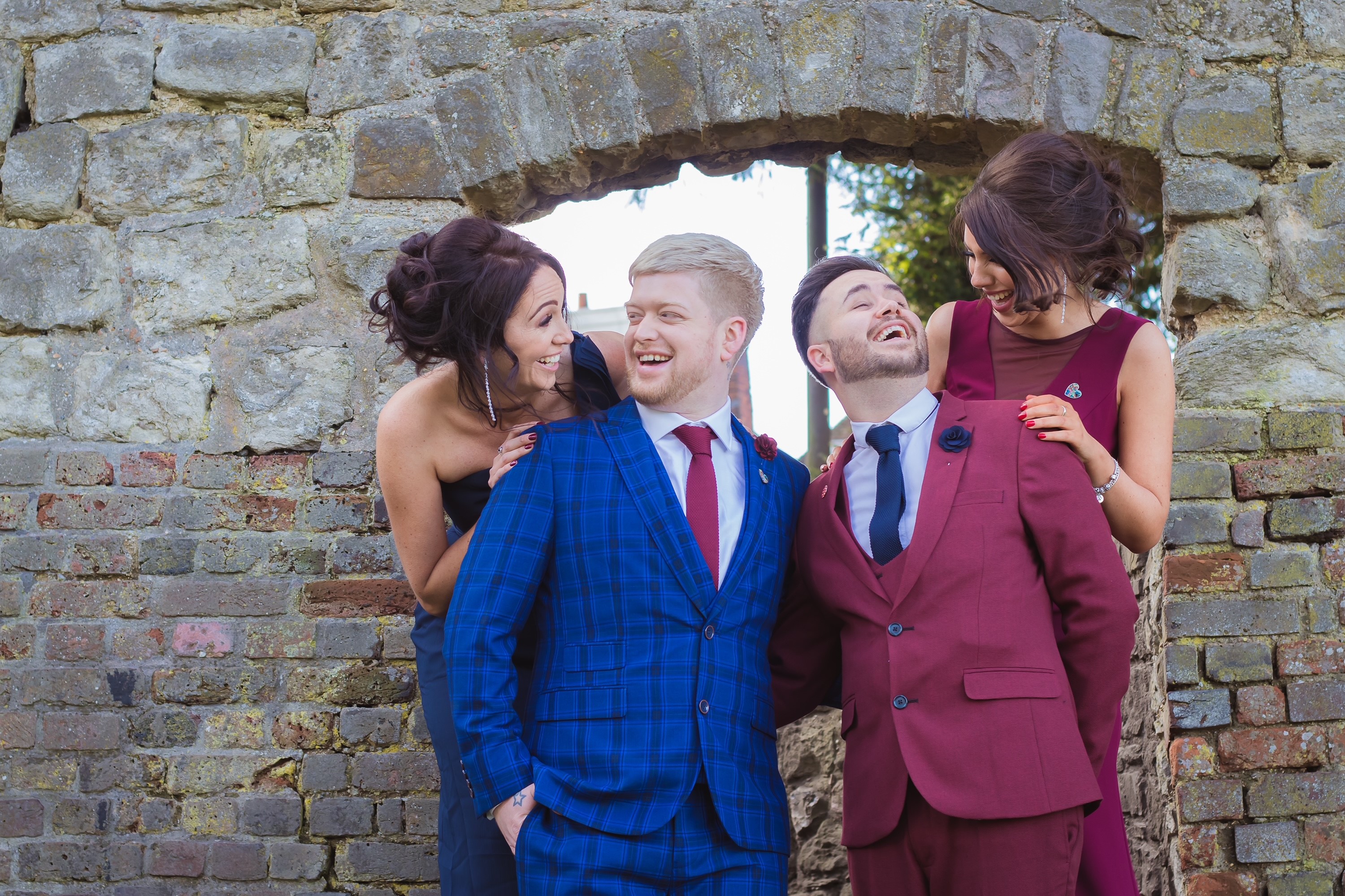 Two grooms and two bridesmaids laughing.