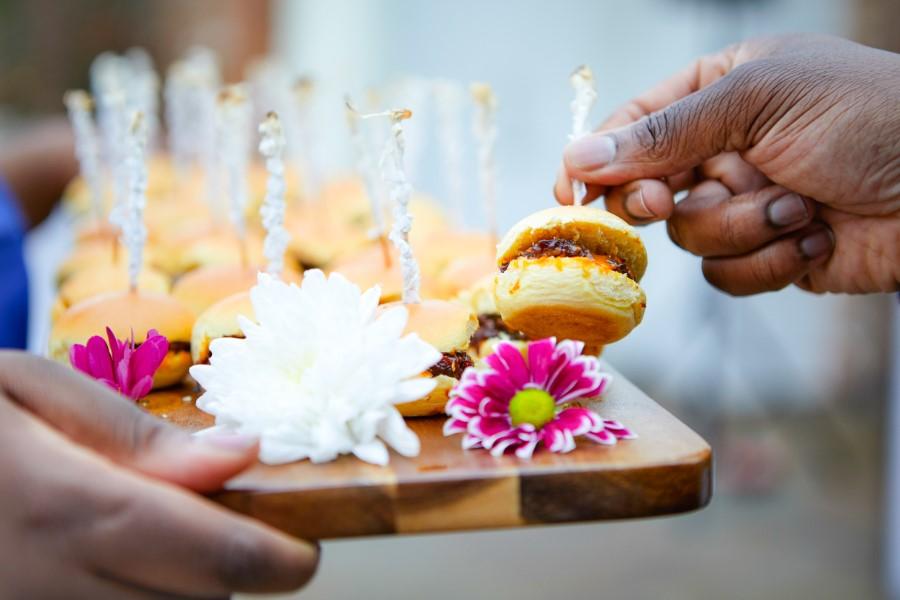 Photograph of BBQ beef brisket mini sliders on wooden board decorated with flowers.