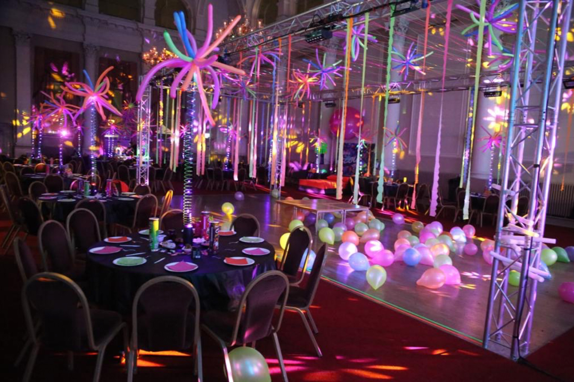 A party room with chairs, balloons and lights.